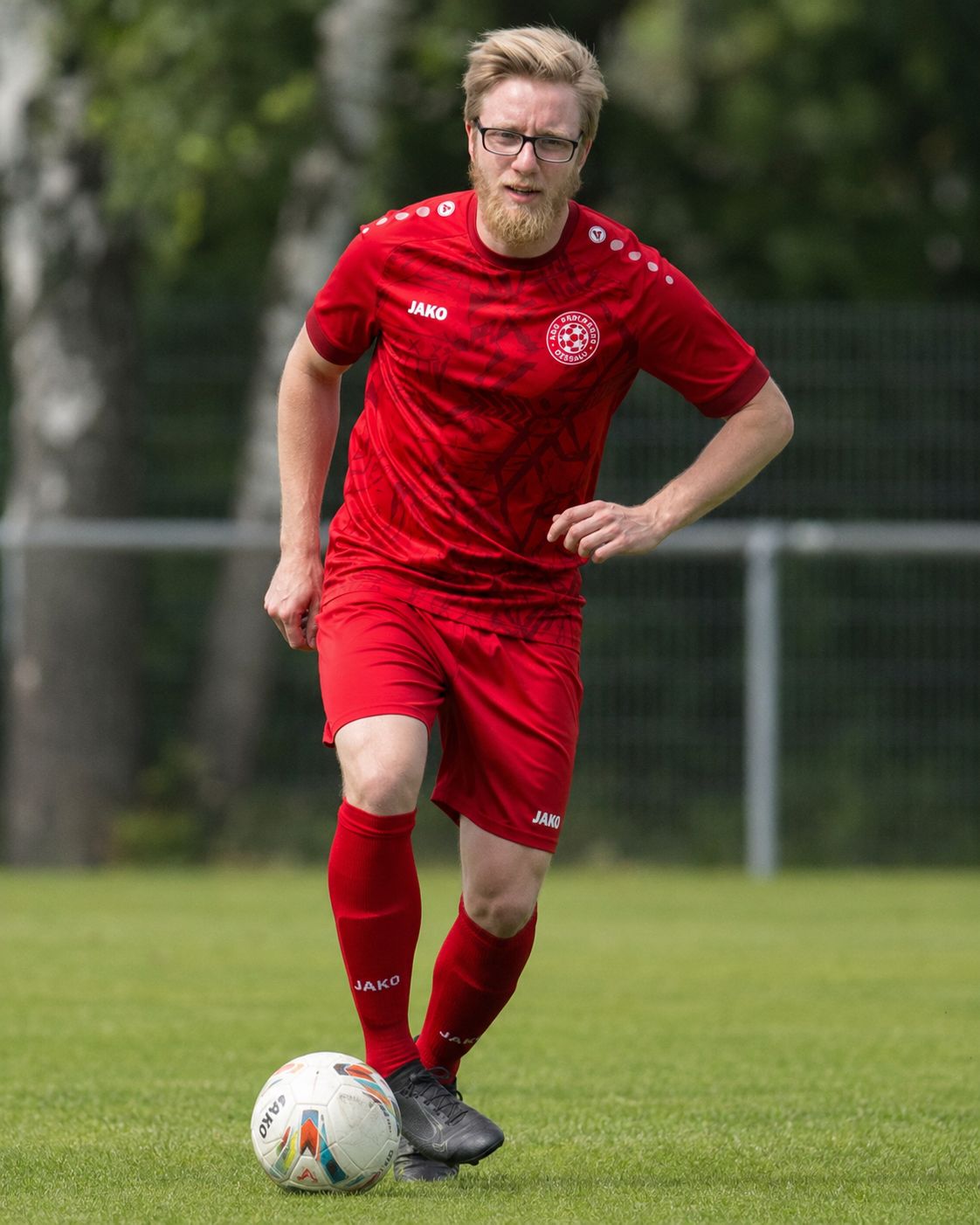 Dennis dribbelt im roten Trikot über den Platz